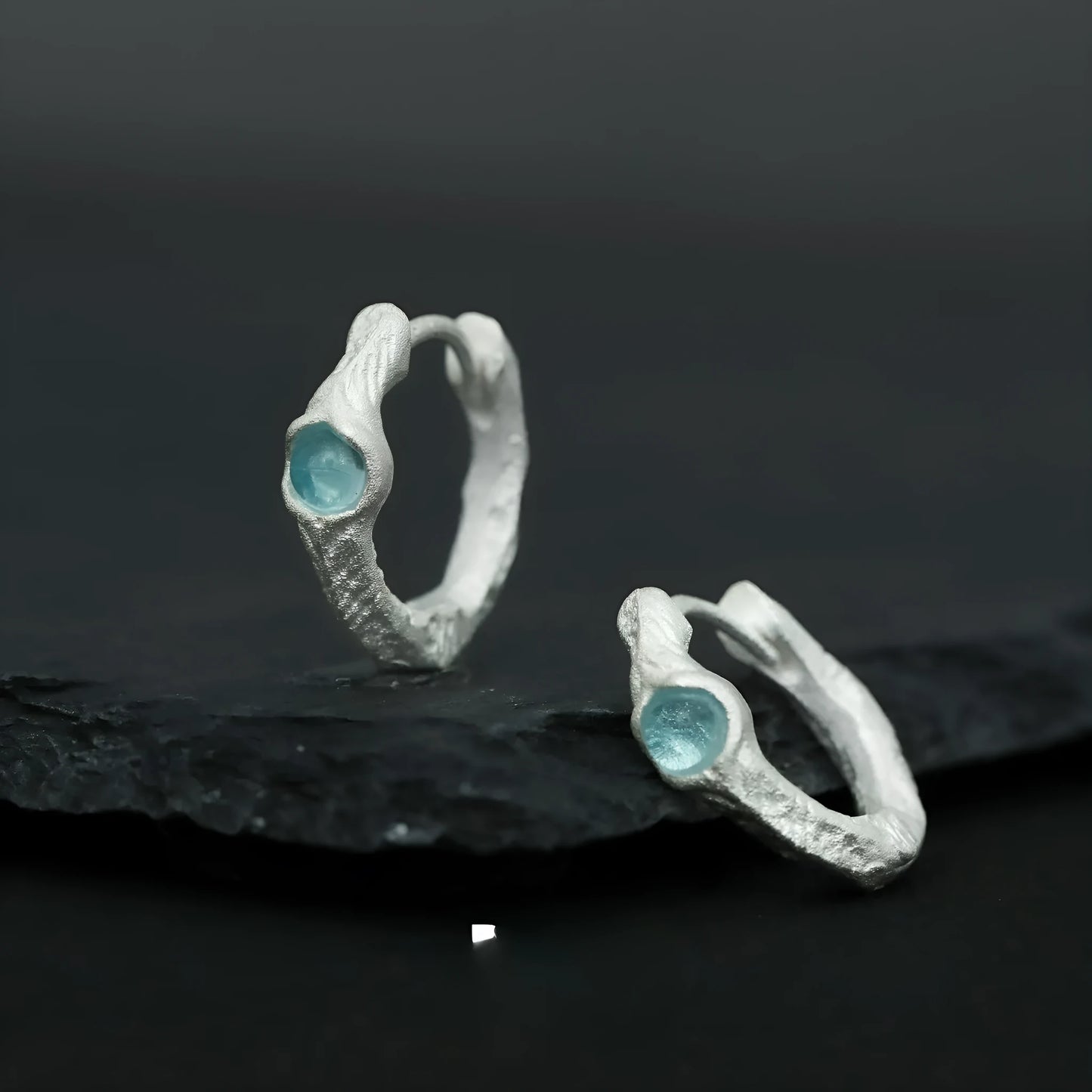 A pair of geometric round ear clips made from 925 silver with a burnt silver electroplated finish.