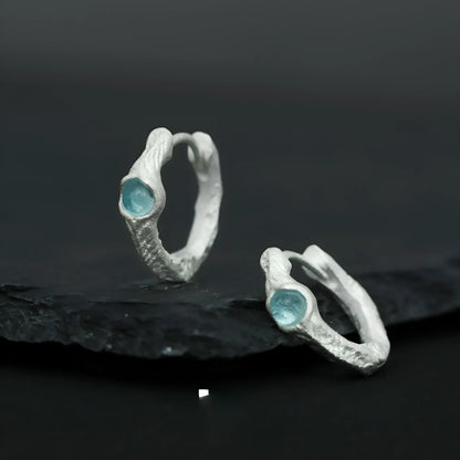 A pair of geometric round ear clips made from 925 silver with a burnt silver electroplated finish.