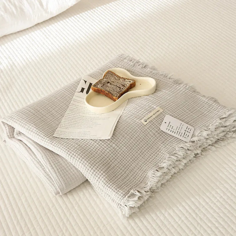 Four-layer gauze tassel blanket in cotton, showing tassel edges and textured fabric, available in multiple colours and sizes