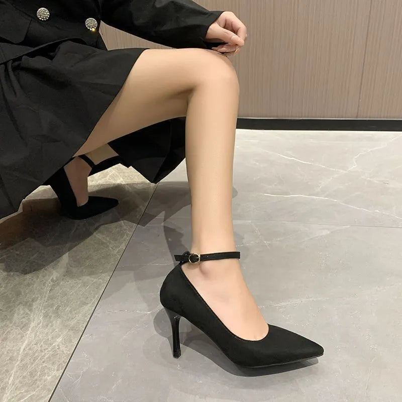 Women's black stiletto heels with skull pattern and ankle buckle closure on wooden floor