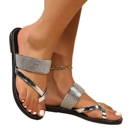 Women's flat beach sandals with a rhinestone-decorated toe strap in gold colour on a rubber sole.
