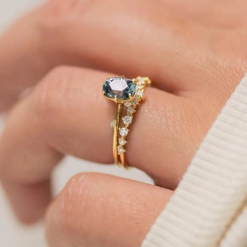 Gold-plated floral women's ring with a central green zircon stone on a model's hand.