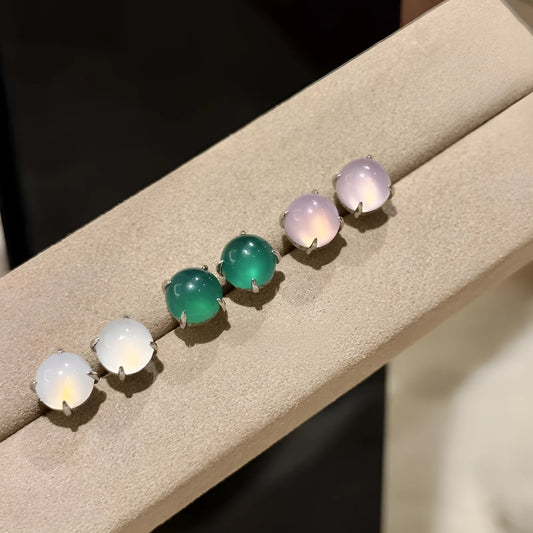 Close-up of a Chinese retro style stud earring with a round green chalcedony stone in a four-claw copper setting.