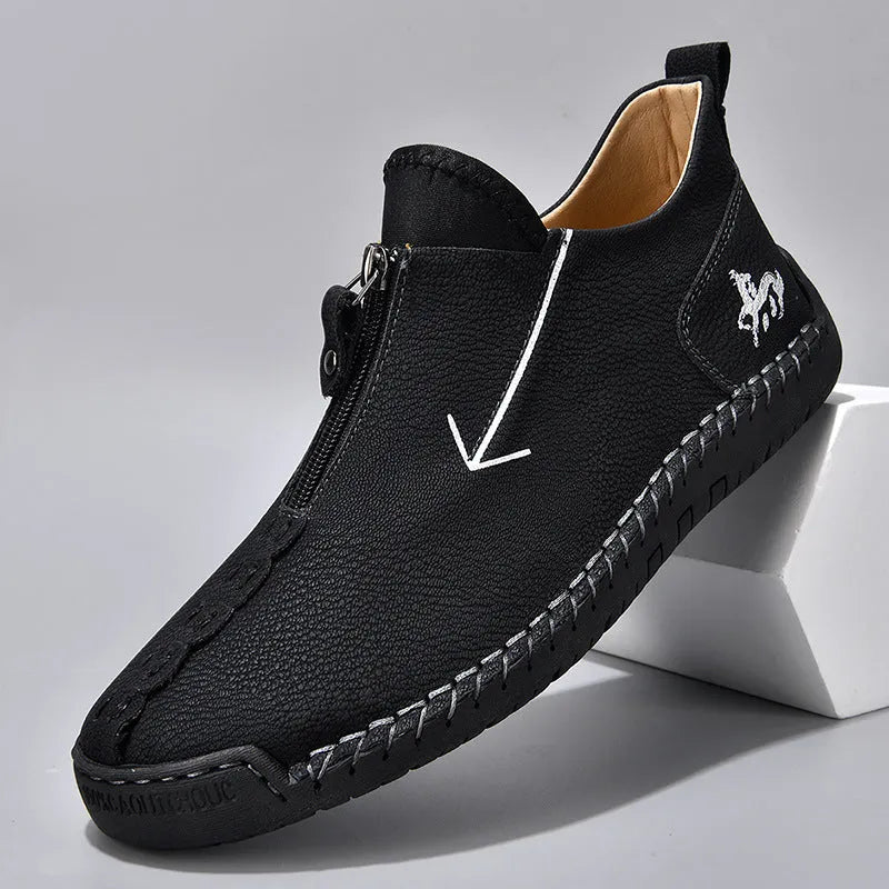 Men's black leather boots with front zipper, hand-stitched detailing, and rubber sole on a neutral background