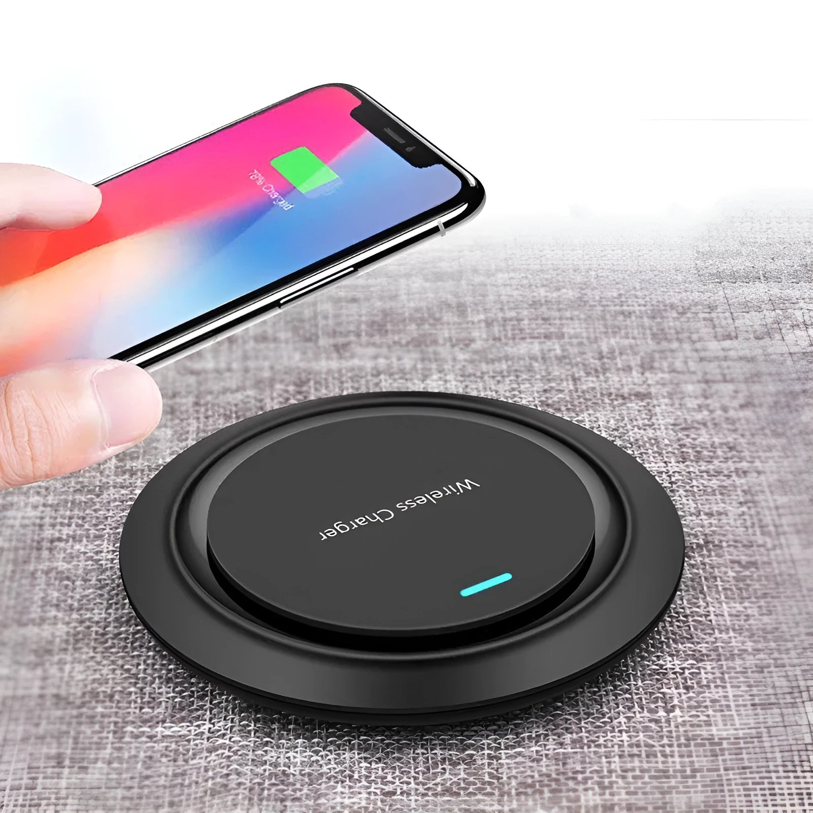 Round white wireless charging pad on desk next to mobile phone