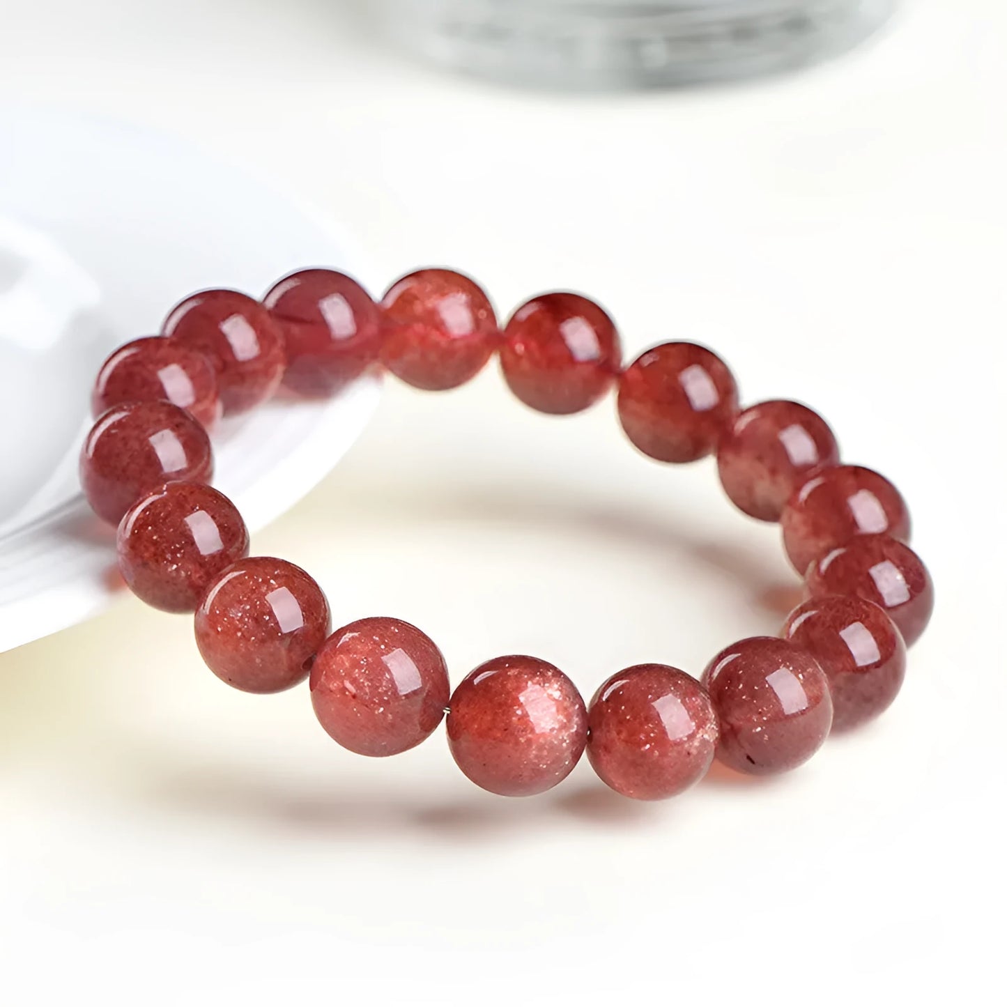 A polished strawberry quartz crystal bracelet in cherry red on a white background, showing geometric beads.