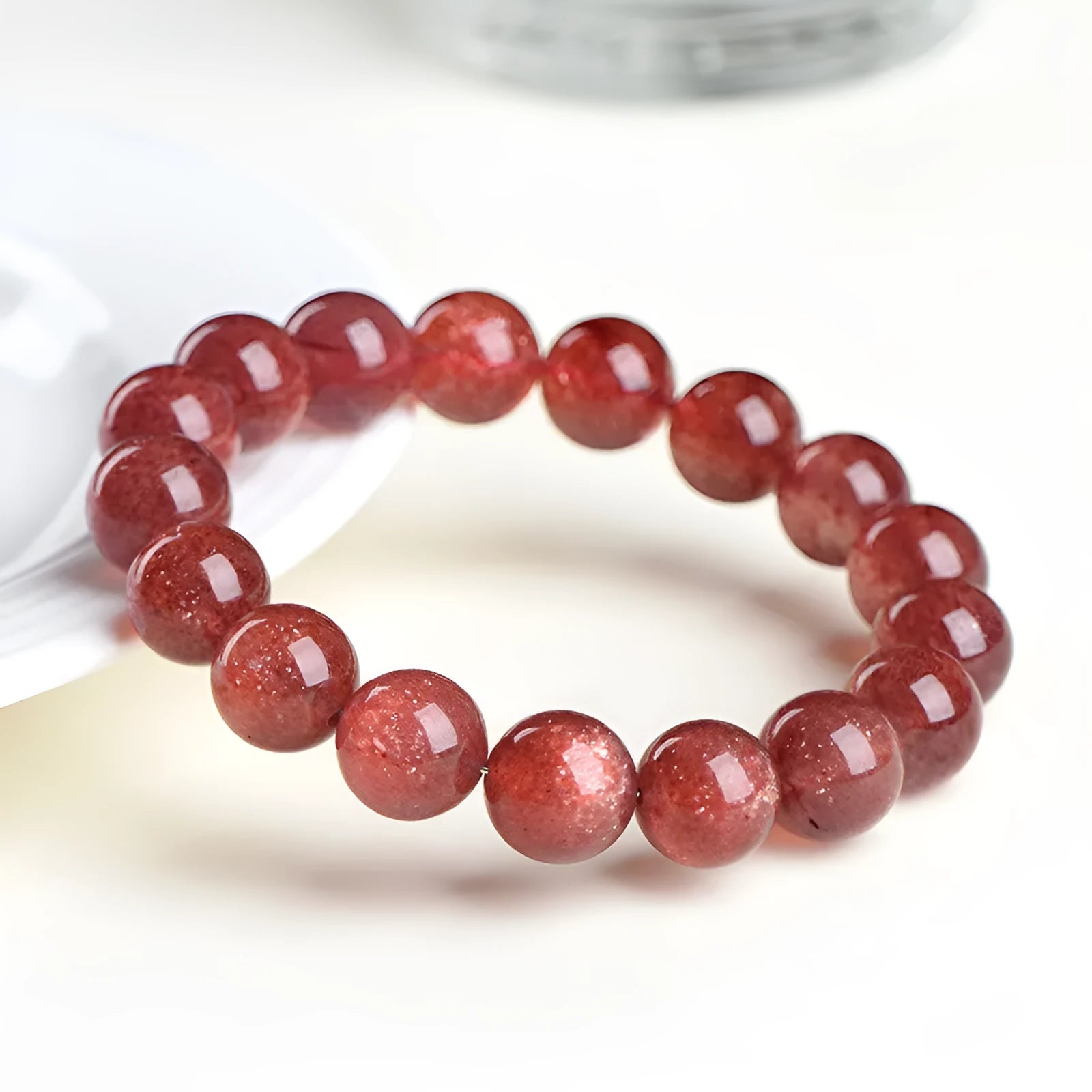 A polished strawberry quartz crystal bracelet in cherry red on a white background, showing geometric beads.