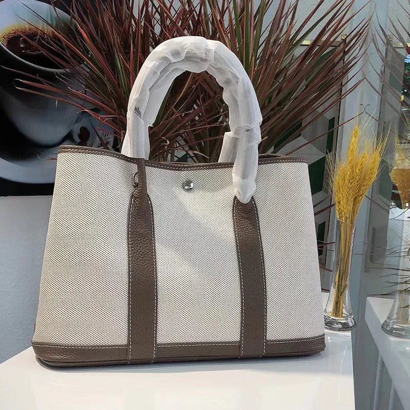 Genuine leather and canvas women's tote bucket bag in black, shown with a soft carry handle.