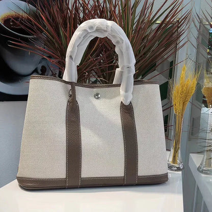 Genuine leather and canvas women's tote bucket bag in black, shown with a soft carry handle.