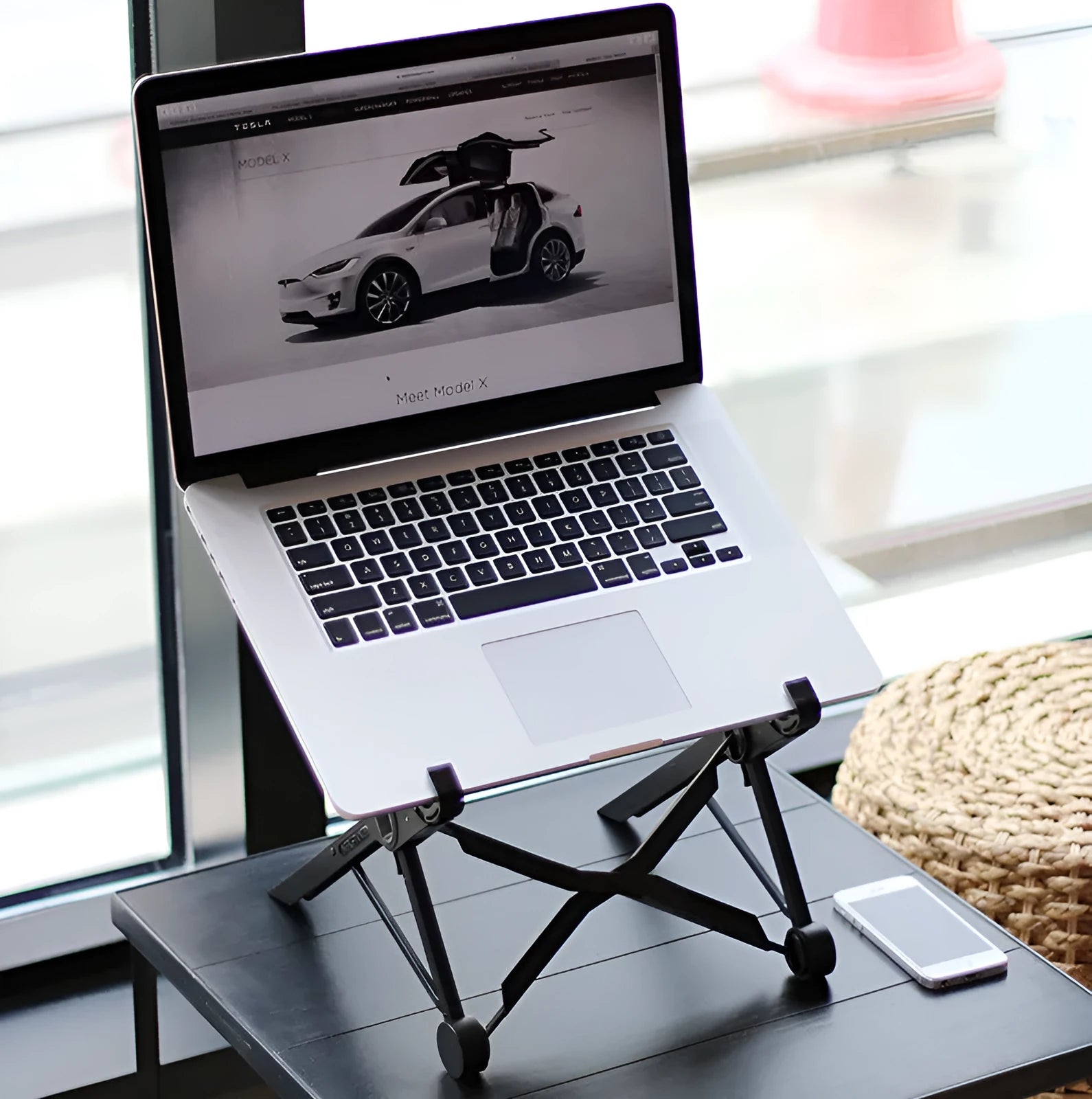 Black folding portable laptop stand with aluminium frame, shown open supporting a laptop and folded to 4cm thickness.