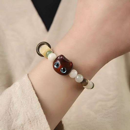 Hand-woven multi-treasure bracelet with jade, bodhi and ebony wood beads and a cartoon cat's paw charm.
