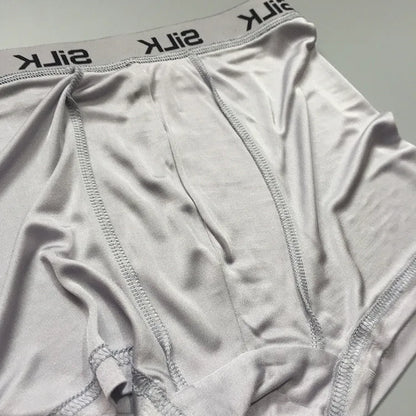 Men's loose-fitting silk shorts in navy blue on a neutral background.