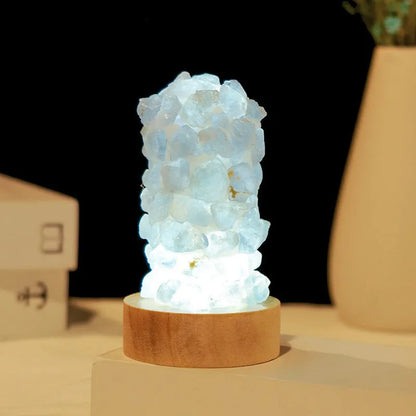Miniature amethyst crystal tooth flower night light glowing with warm light on a wooden surface.