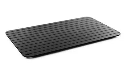 Black aluminium fast defrosting tray for kitchen use, shown thawing frozen meat.