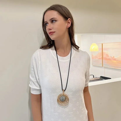 Gold geometric plaid pendant necklace on a textured snakeskin-style rope chain, laid out to show length.