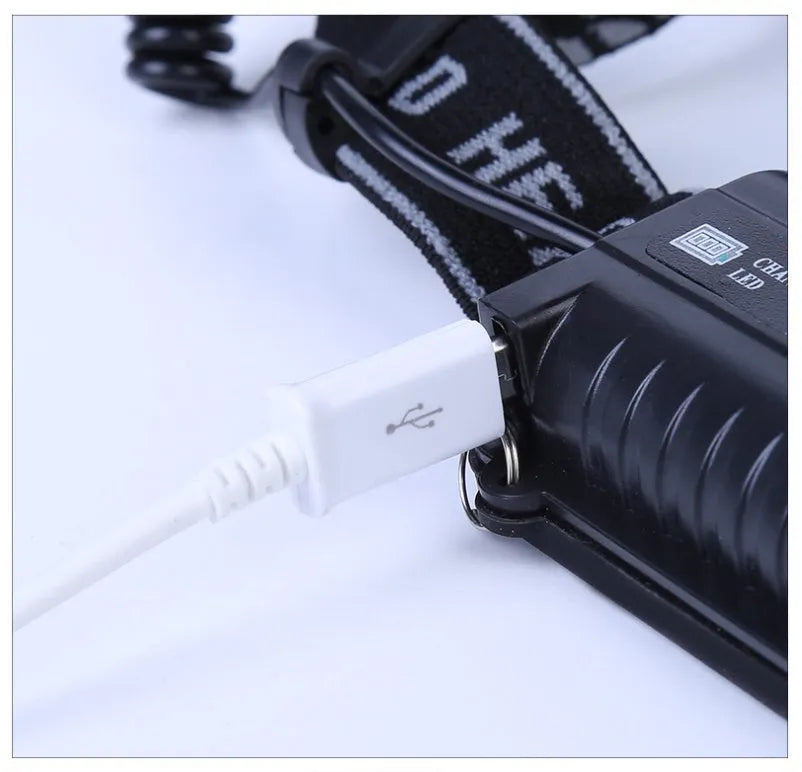 Fixed focus head torch for camping with long-range LED beam, shown with charger.