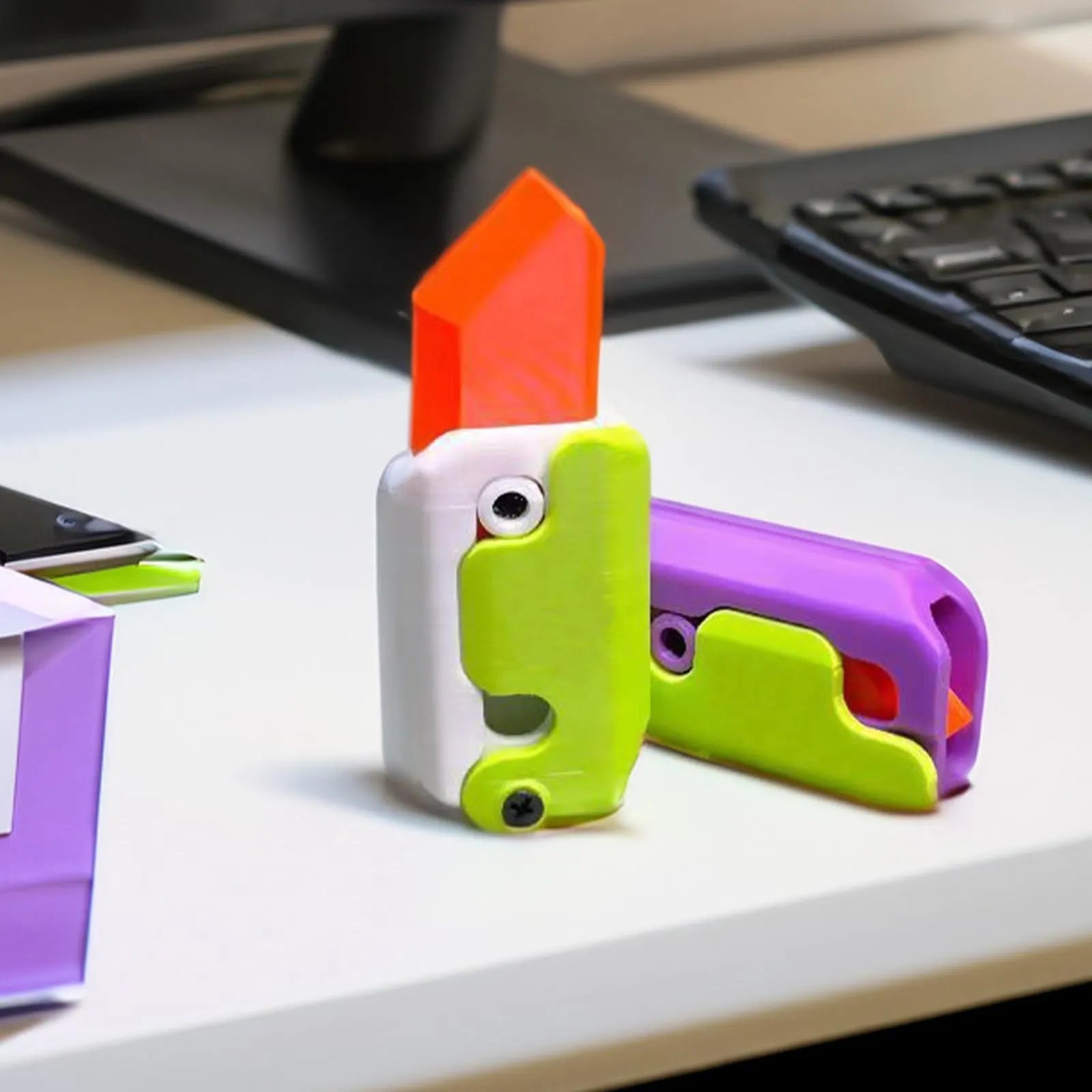 Small orange and green 3D printed plastic carrot knife fidget toy with blade extended.