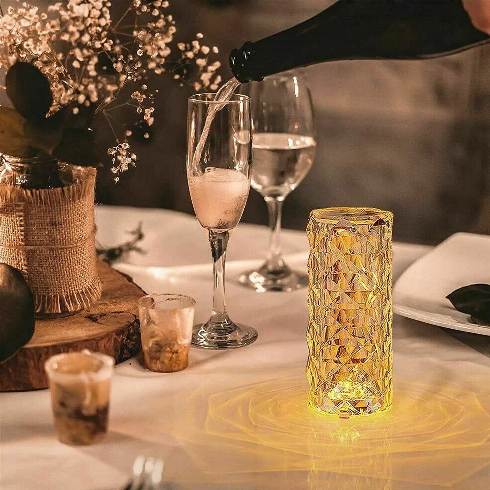 Clear acrylic LED table lamp with diamond-cut surfaces and remote control on wooden surface