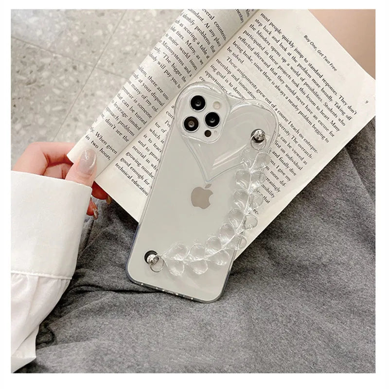 Transparent TPU iPhone case with love bracelet and heart chain design on a table.
