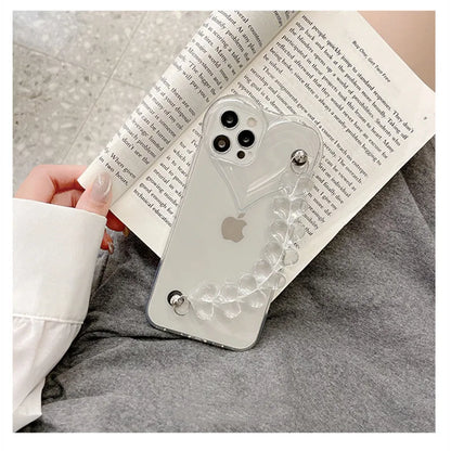 Transparent TPU iPhone case with love bracelet and heart chain design on a table.