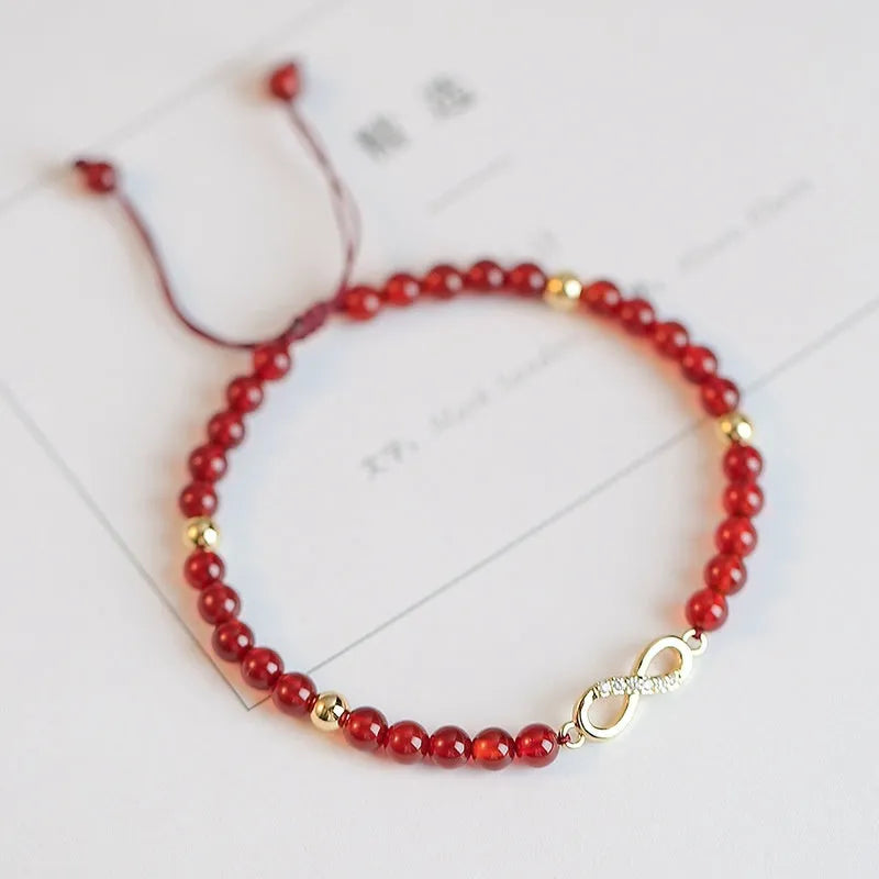 Hand-woven red agate beads bracelet with lucky charm in ethnic style, showing diamond-shaped beads.