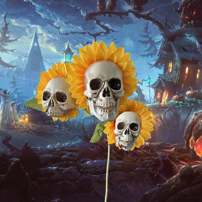 A group of skull-shaped sunflower ornaments arranged in a Halloween-themed outdoor display