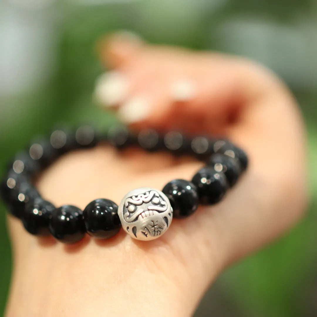 A bracelet with large black agate beads and a sterling silver clasp on a wrist.