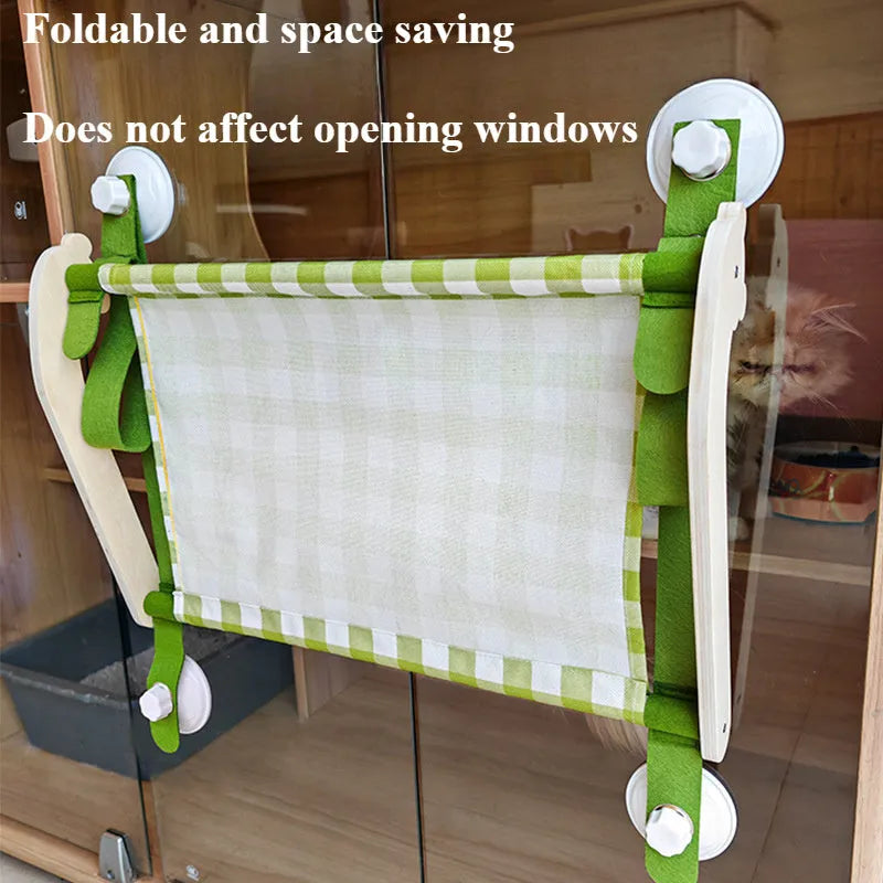 Pink cat hammock with wooden frame and suction cups attached to a window, with a cat resting inside.