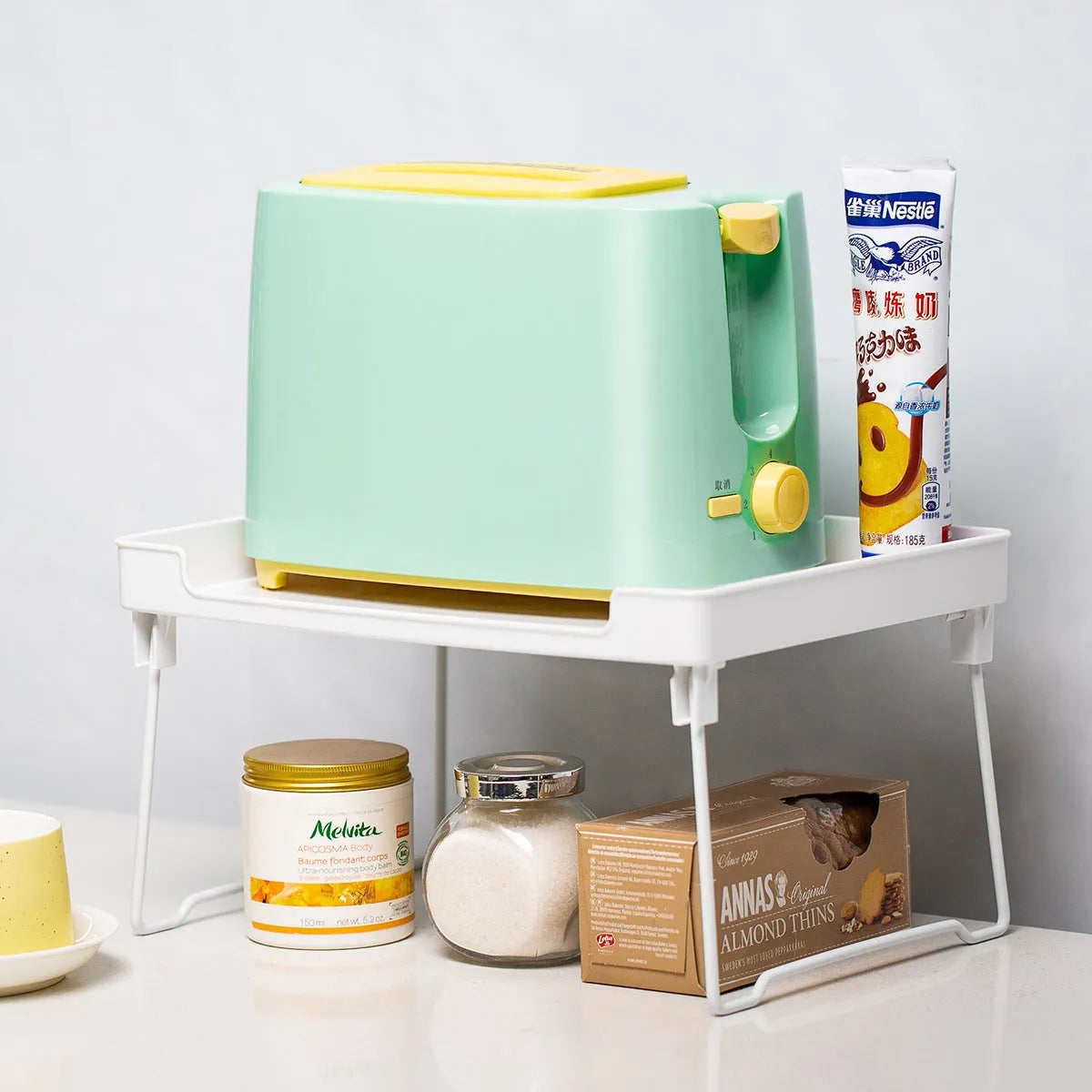 Transparent and white plastic kitchen supplies rack with multiple compartments for drawer and shelf organisation