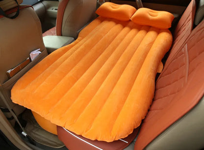 Black inflatable car bed with flocked surface and two pillows, shown folded into a chair inside a vehicle.