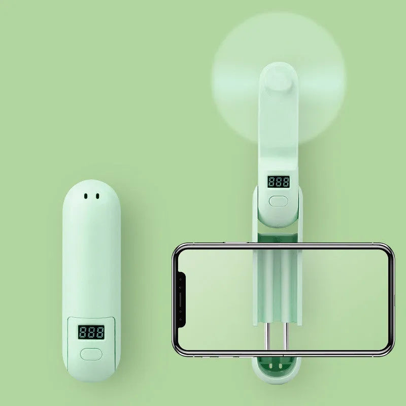 Green folding mini fan with plastic leaves in open position showing compact USB-rechargeable design