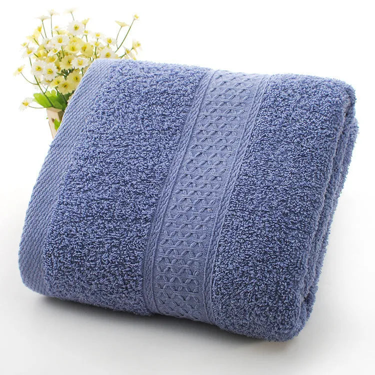 A stack of thickened cotton bath and beach towels in various colours including apple green, dark blue, and light pink.