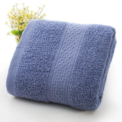 A stack of thickened cotton bath and beach towels in various colours including apple green, dark blue, and light pink.