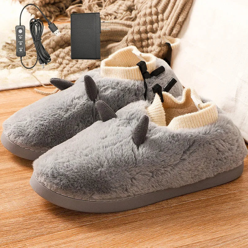 USB heated slippers in grey with a USB cable plugged into a power bank, showing the enclosed velvet design.