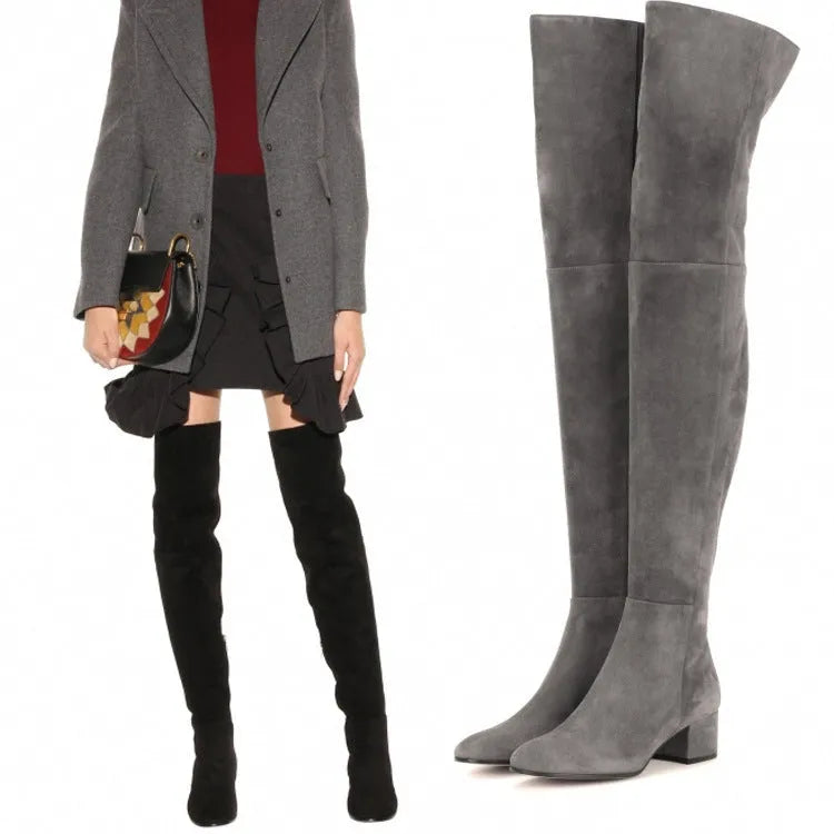 Women's grey suede over-the-knee flat boots with pointed toe and thick rubber sole on a neutral background
