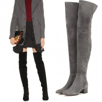 Women's grey suede over-the-knee flat boots with pointed toe and thick rubber sole on a neutral background