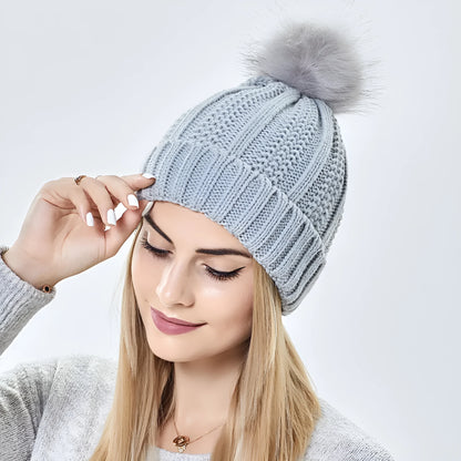 Wool knit beanie hat for women with faux fur pom pom and satin lining, shown in a wine red colour.