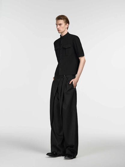 Black straight-leg trousers with an adjustable mid-waistband and single pleat detail on a hanger.