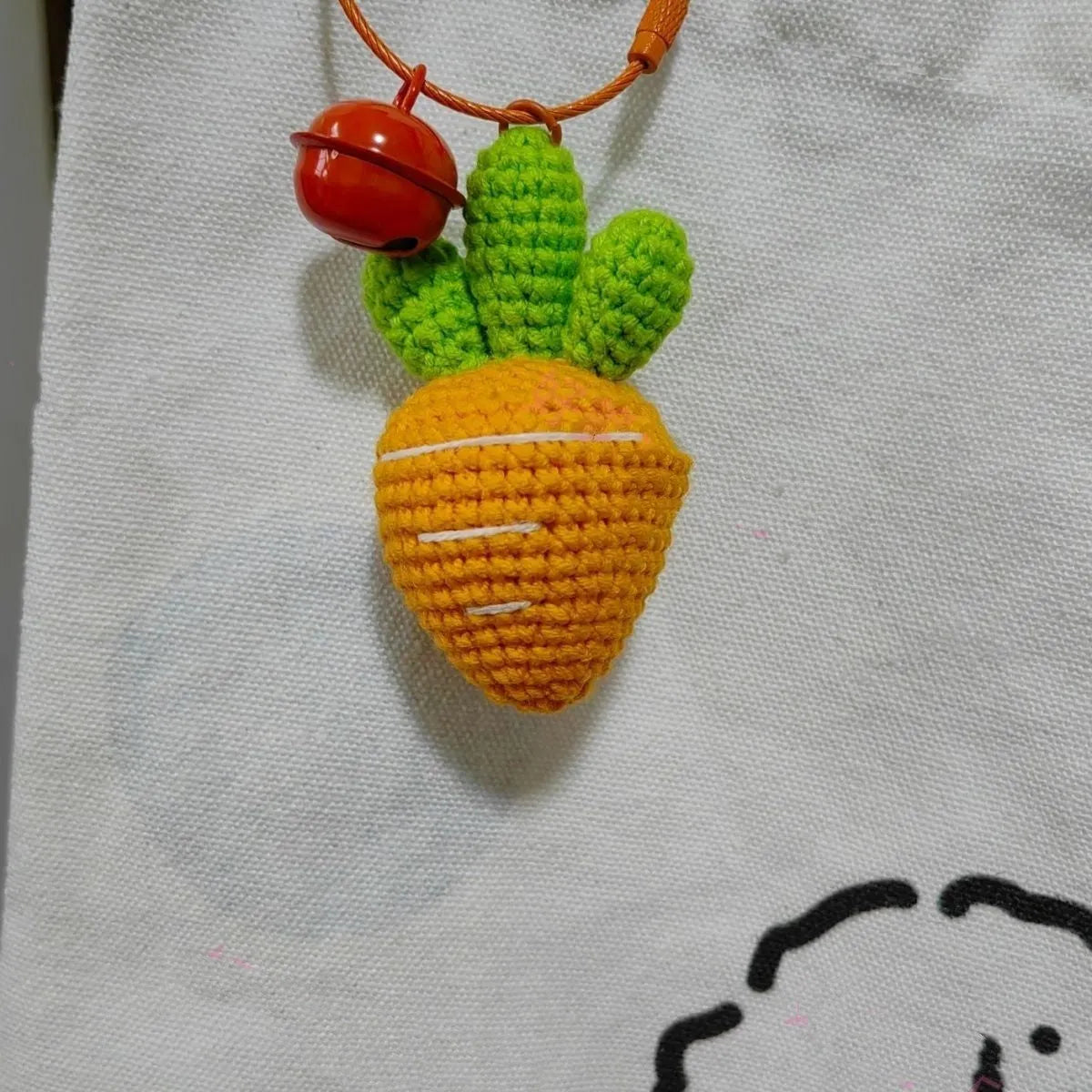 Cartoon carrot car design wool felt keychain pendant on a keyring.