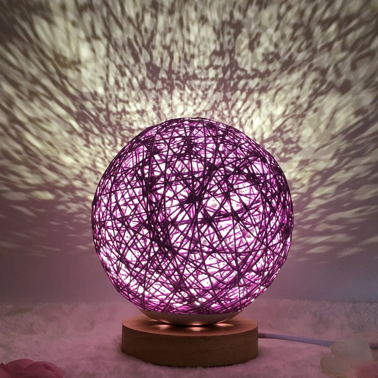 Spherical hand-knitted rattan table lamp with remote control on a wooden desk