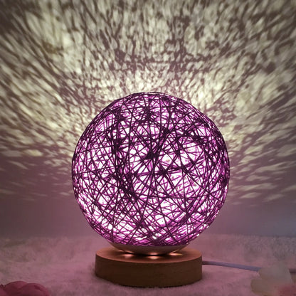 Spherical hand-knitted rattan table lamp with remote control on a wooden desk