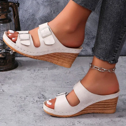Women's creamy-white wedge slippers with an outer belt buckle and a rubber sole.