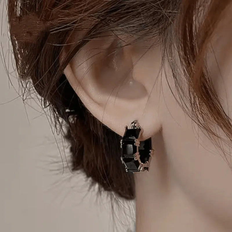 A pair of geometric U-shaped copper earrings with a round zircon stone in a gold-coloured setting.