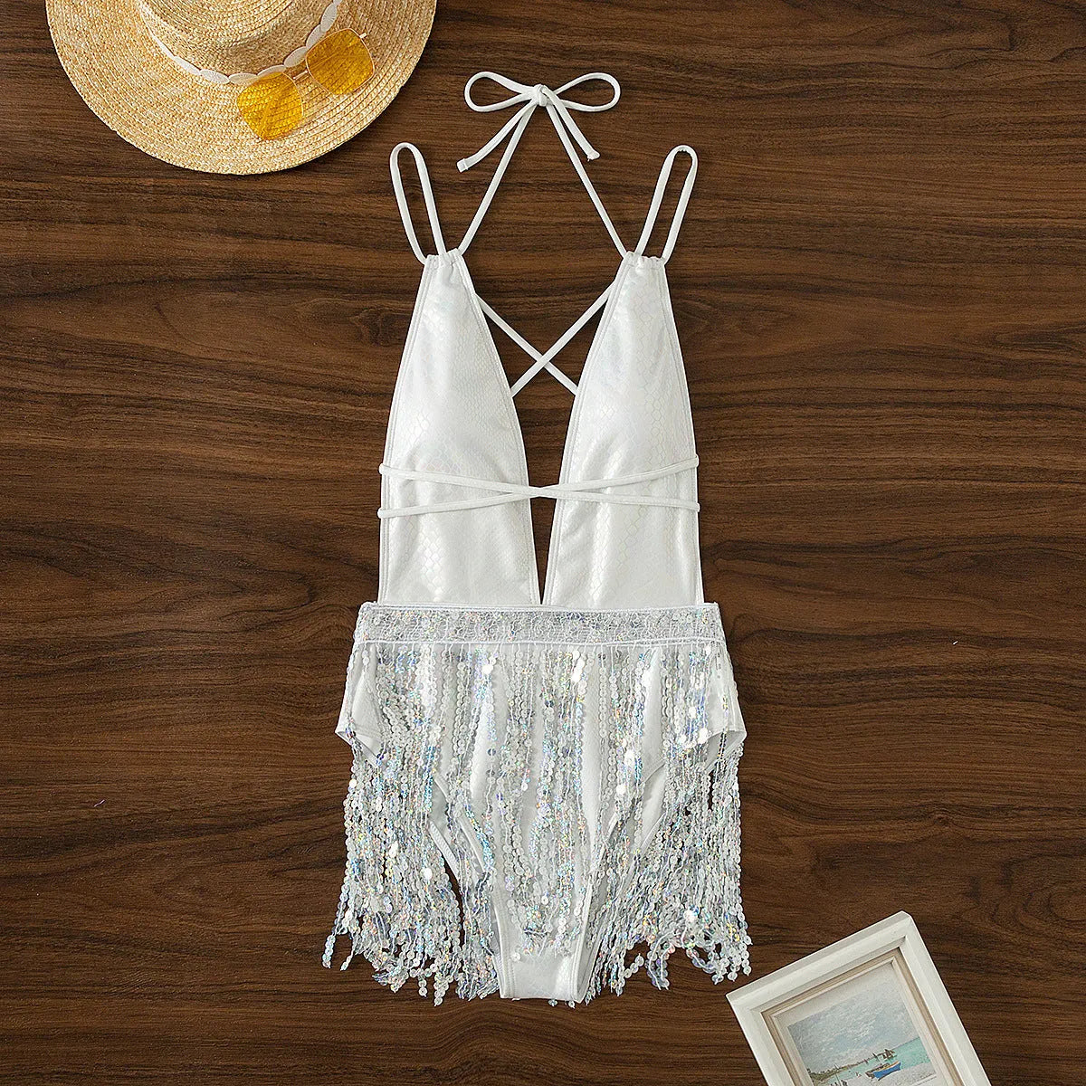 White one-piece swimsuit with deep V-neck and tassel detail, sleeveless brief style.