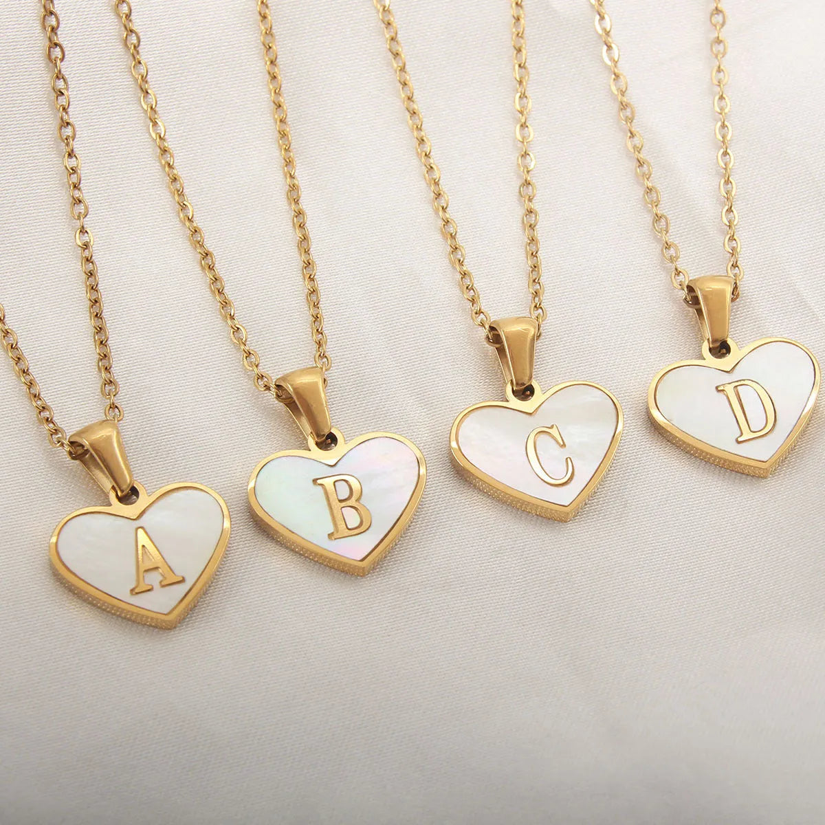 Gold-plated clavicle necklace with a white shell heart pendant, personalised with a letter from A to Z.