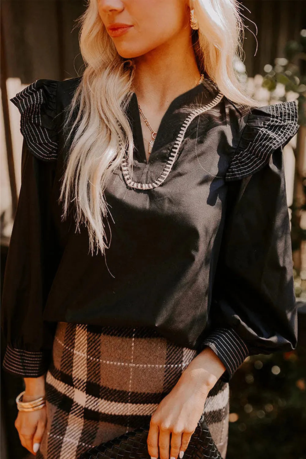 Black women's V-neck blouse with contrast stitching on neckline and long sleeves, ruffle detail