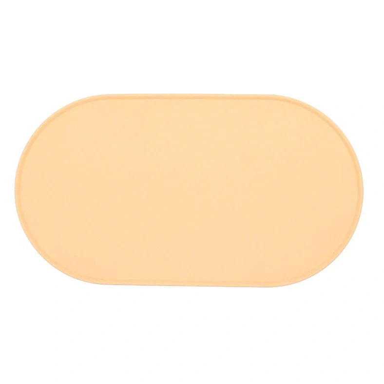 Green silicone cat feeding placemat with raised edges on wooden floor containing water bowl