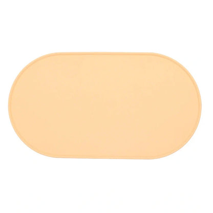 Green silicone cat feeding placemat with raised edges on wooden floor containing water bowl