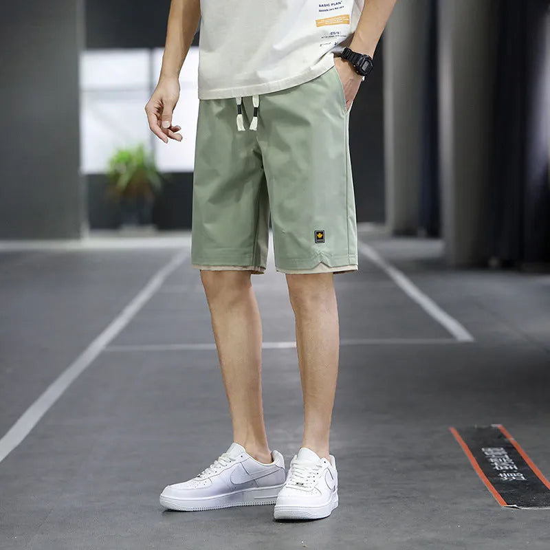 Man wearing loose straight-leg beach shorts in khaki, showcasing the South Korean style fit and micro-elastic waistband.