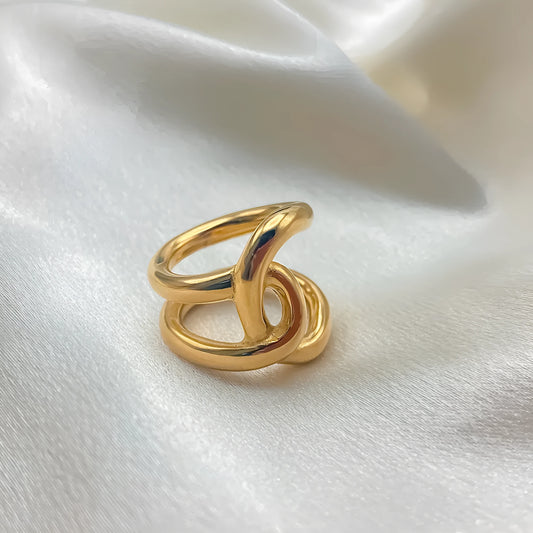 Knotted adjustable stainless steel ring for women in gold or steel colour on a grey background.